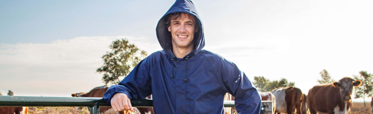 Boer in blauwe overall met koeën op de achtergrond 